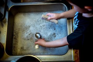 Child at sink washing pots chronic illness and housekeeping 